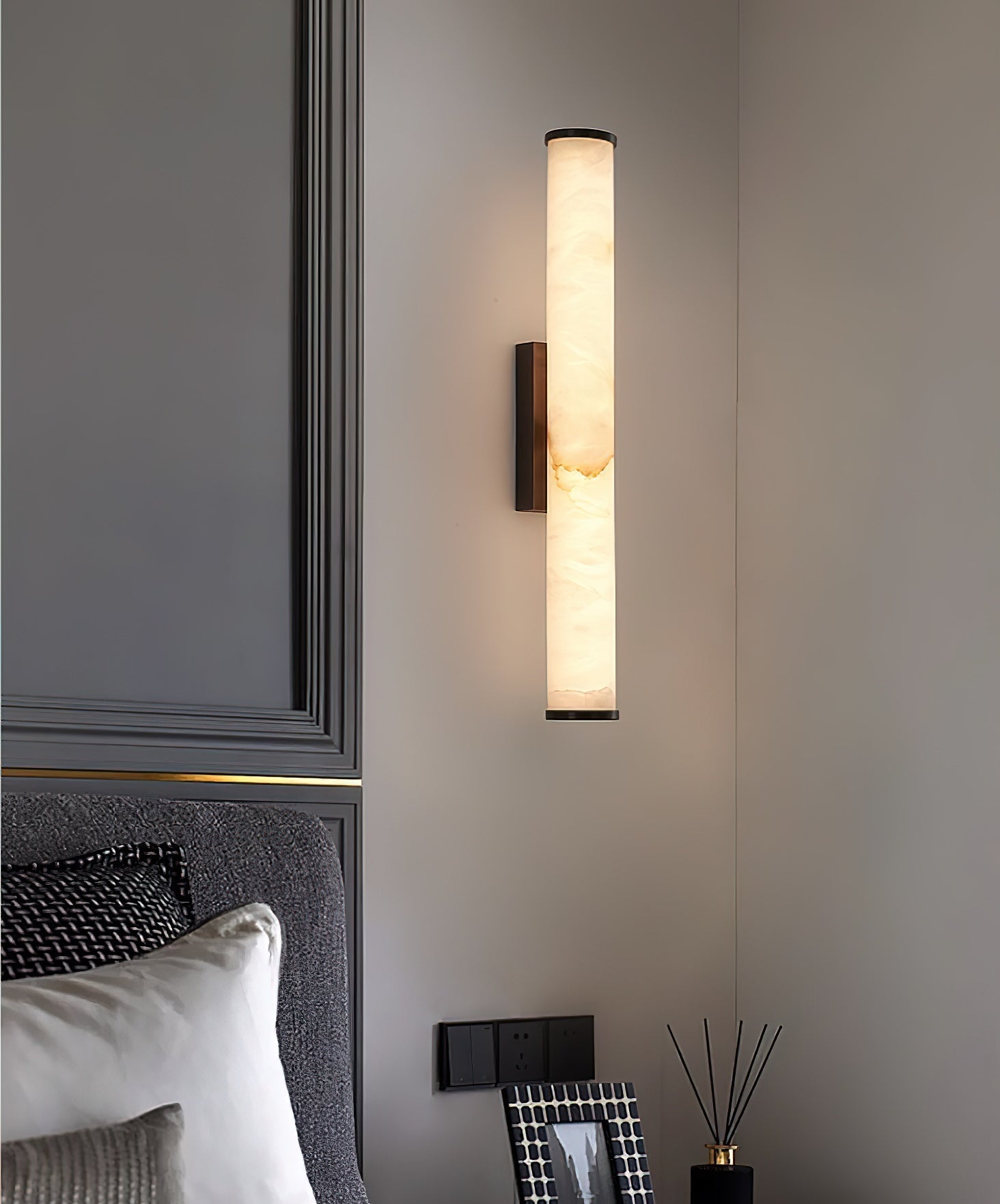 Clérachic sconce on grey panelled joinery, warm light falling across a reed diffuser and framed print.