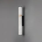 The Clérachic sconce in black, its full alabaster column shown flat-on against a soft grey studio wall.