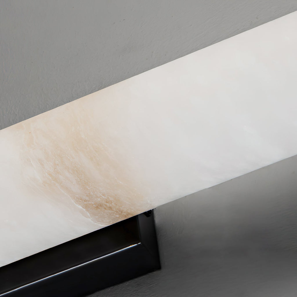 The Clérachic sconce seen from beneath, pale alabaster edge and black bracket against a white ceiling line.