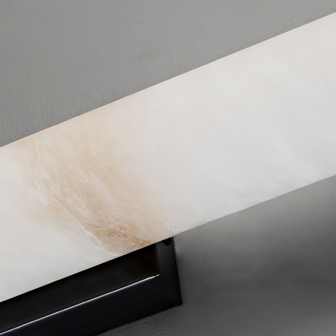 The Clérachic sconce seen from beneath, pale alabaster edge and black bracket against a white ceiling line.