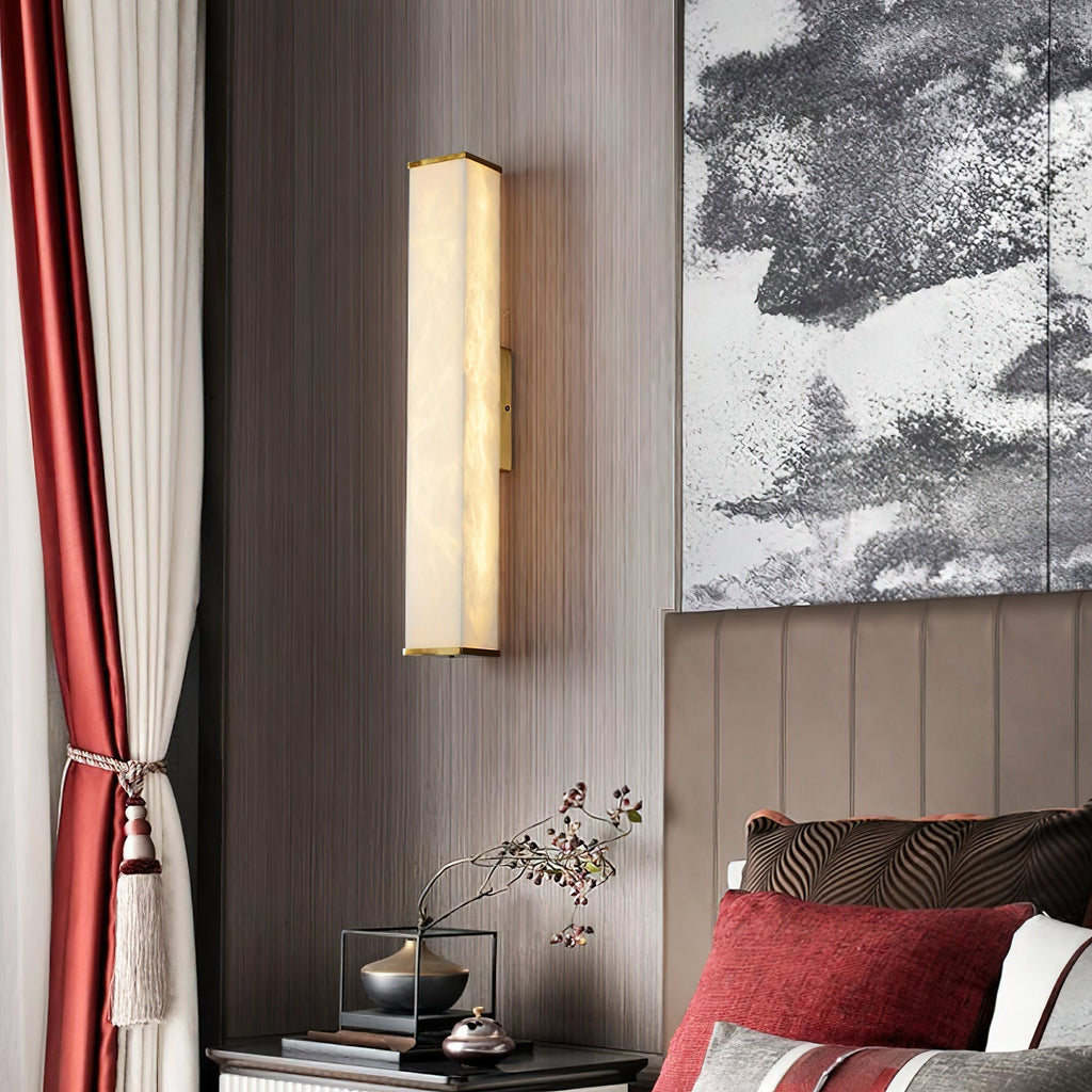 The Clérachic sconce lighting a bedroom with red drapery and monochrome art, brass caps catching the glow.