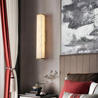 The Clérachic sconce lighting a bedroom with red drapery and monochrome art, brass caps catching the glow.