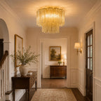 Pale champagne-yellow Clérachic flush mount lighting a hallway with panelled walls, a dark timber console and a landscape painting.