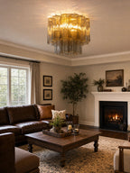 Amber glass Clérachic flush mount above a living room with a brown leather sofa, a square timber coffee table and a lit fireplace.