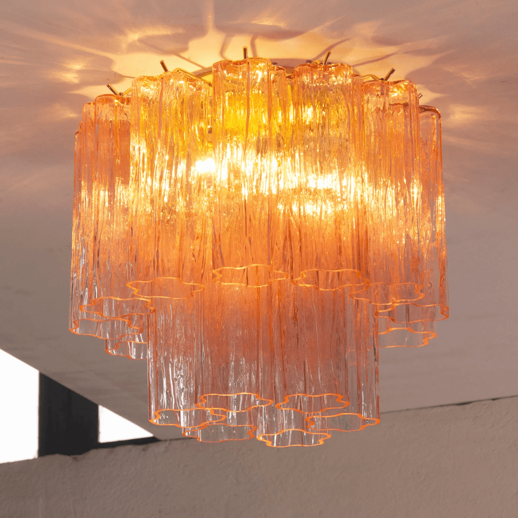 Looking up at the pink and apricot glass tubes of this Clérachic flush mount, lit from within and reflecting on the ceiling.