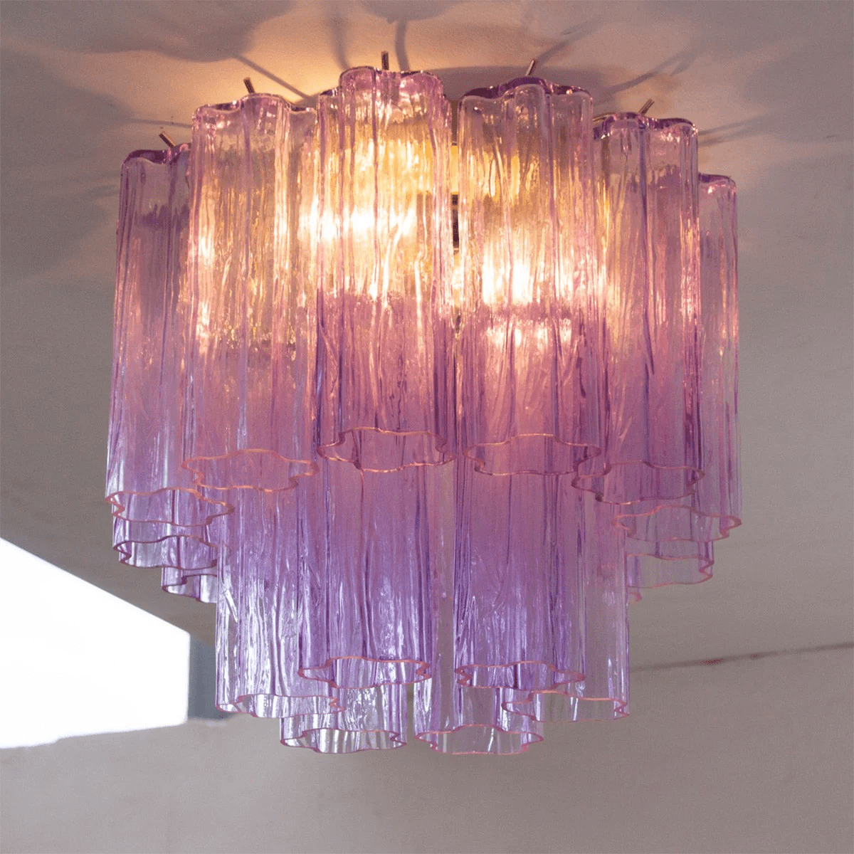 Looking up at the purple art glass tubes of this Clérachic flush mount, lit from within, with the tiers shading to pink at the base.