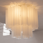 Looking up at the white frosted glass tubes of this Clérachic flush mount, glowing warmly from the bulbs inside.