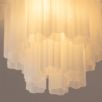 Close view of the frosted white glass tubes on this Clérachic flush mount, lit from within, with their wavy cut ends visible.