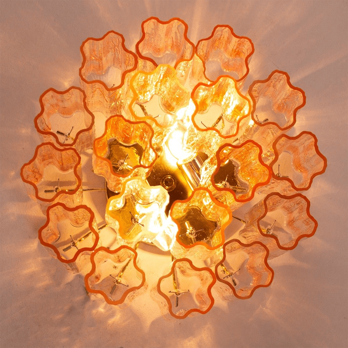 View from directly below this Clérachic flush mount, showing the star-shaped ends of the amber glass tubes around the glowing bulbs.
