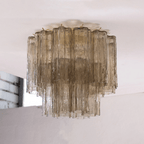 Smoky grey-brown textured glass tubes on this Clérachic flush mount, in two tiers on a white ceiling.