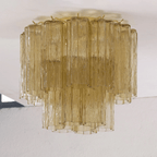 Straight-on view of this Clérachic flush mount in olive-gold glass, with textured tubes in two tiers against a white ceiling.