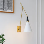 Clérachic wall light with a white cone shade hanging low from a long brass arm, on a pale wall beside a framed black-and-white print.