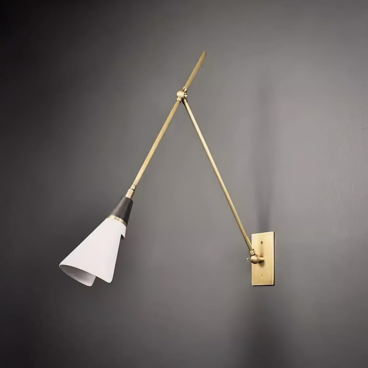 Clérachic wall light on a dark grey wall, with the white cone shade angled down and its rolled edge catching the light.