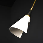 Close view of the white cone shade and black neck of this Clérachic wall light, on a dark backdrop with its lower rim curling inward.