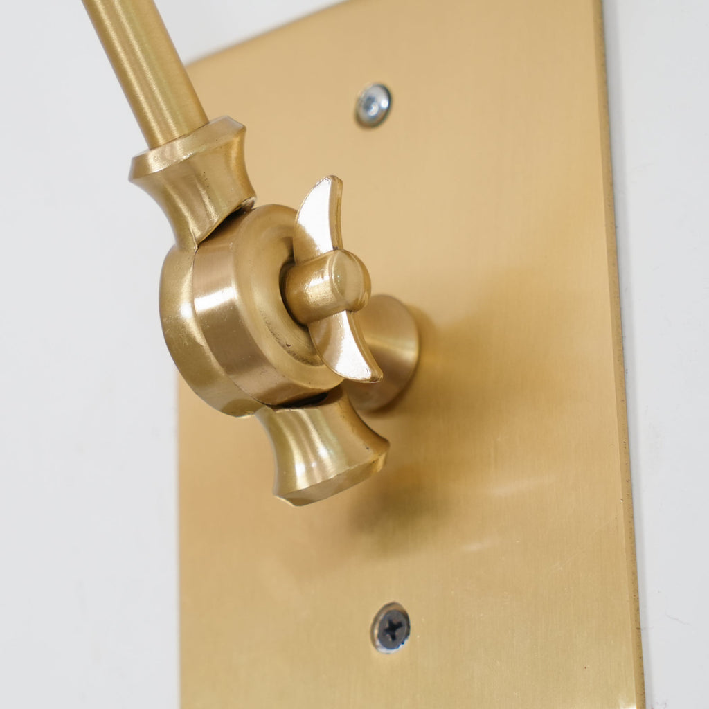 Close view of the brass swivel joint and screw-fixed backplate where the arm of this Clérachic wall light meets the wall.