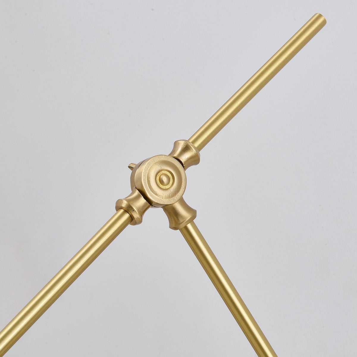 Close view of the round brass joint where two arms of this Clérachic wall light meet, with a ringed centre and tapered ends.