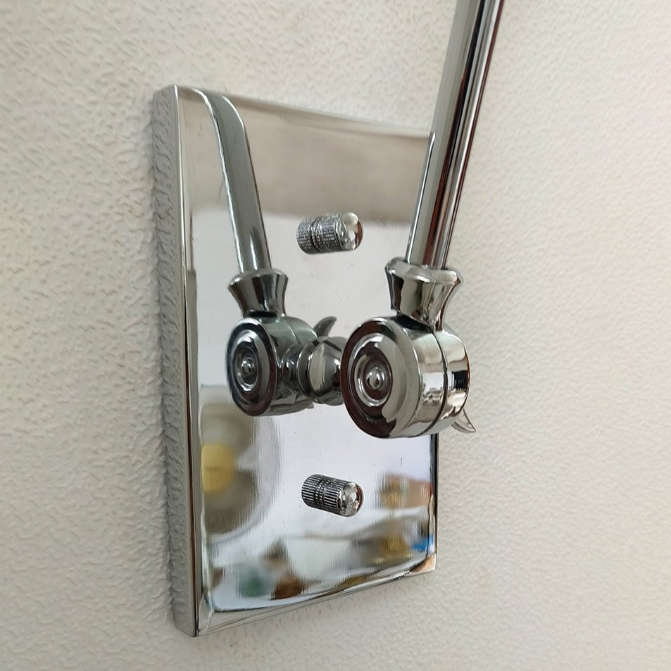 Close view of the polished bright nickel backplate and swivel joints on this Clérachic wall light, fixed to a textured wall.