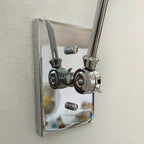 Close view of the polished bright nickel backplate and swivel joints on this Clérachic wall light, fixed to a textured wall.