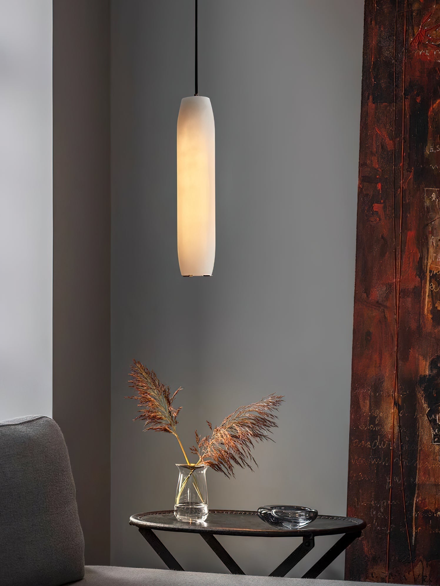 The Clérachic Asbury lights a corner of weathered rust-red timber, above a round table holding dried pampas grass.