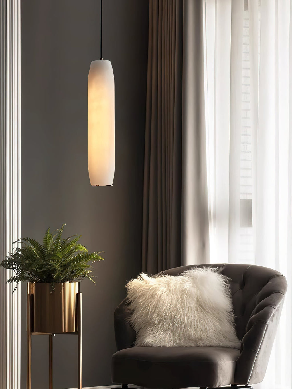 Clérachic hangs the Asbury by tall curtains, its alabaster shade lit above a charcoal armchair and a brass planter.