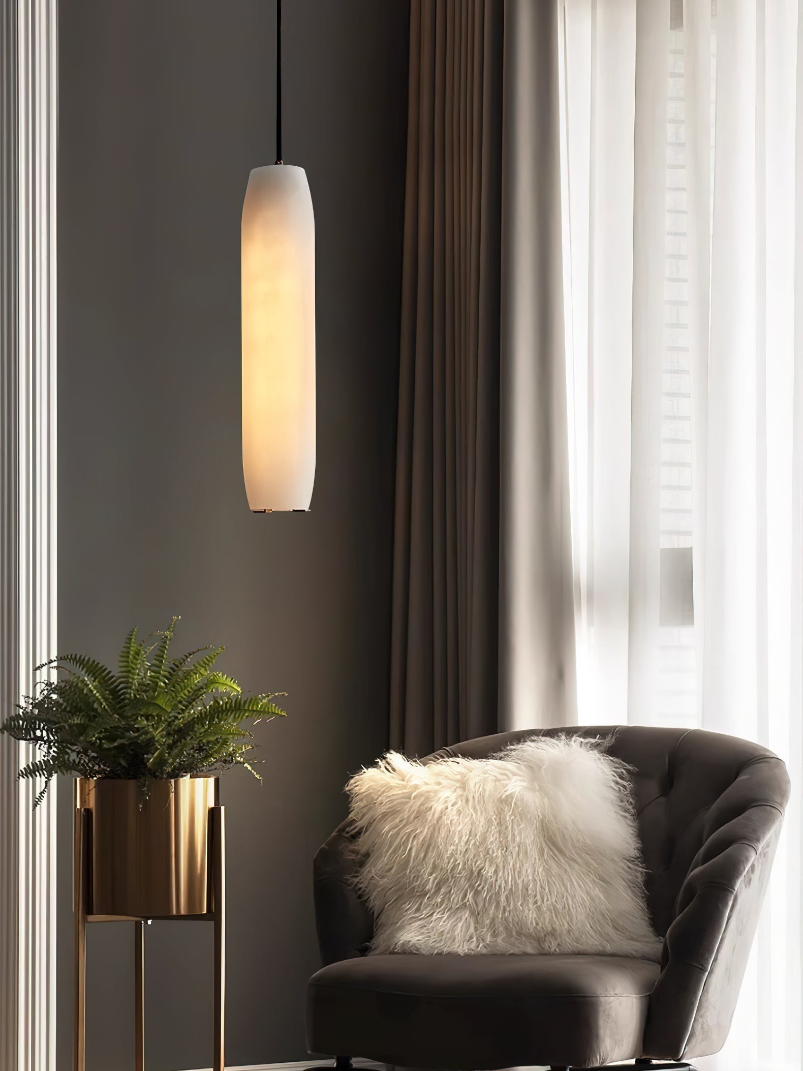 Clérachic hangs the Asbury by tall curtains, its alabaster shade lit above a charcoal armchair and a brass planter.
