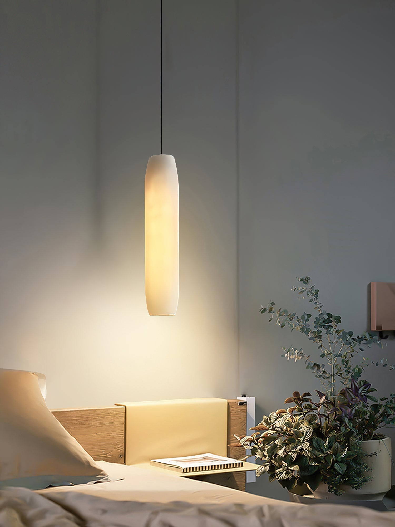 Clérachic warms a dark bedroom wall with the Asbury pendant, spilling light over an open book and trailing greenery.