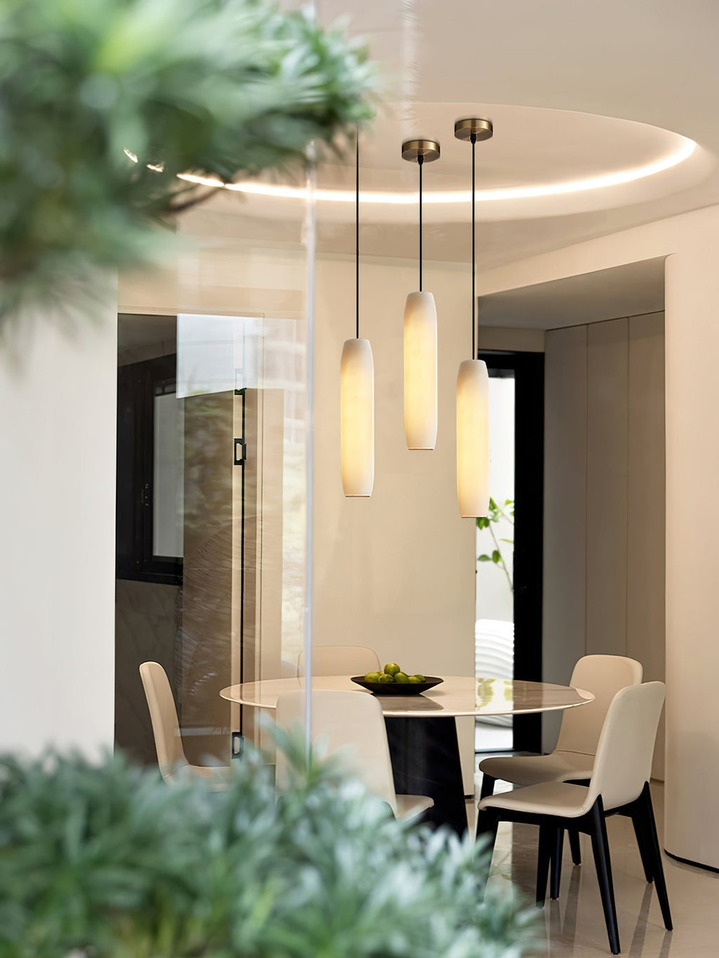 The Clérachic Asbury repeats over a round dining table, three alabaster shades seen past a blurred green branch.