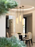 The Clérachic Asbury repeats over a round dining table, three alabaster shades seen past a blurred green branch.