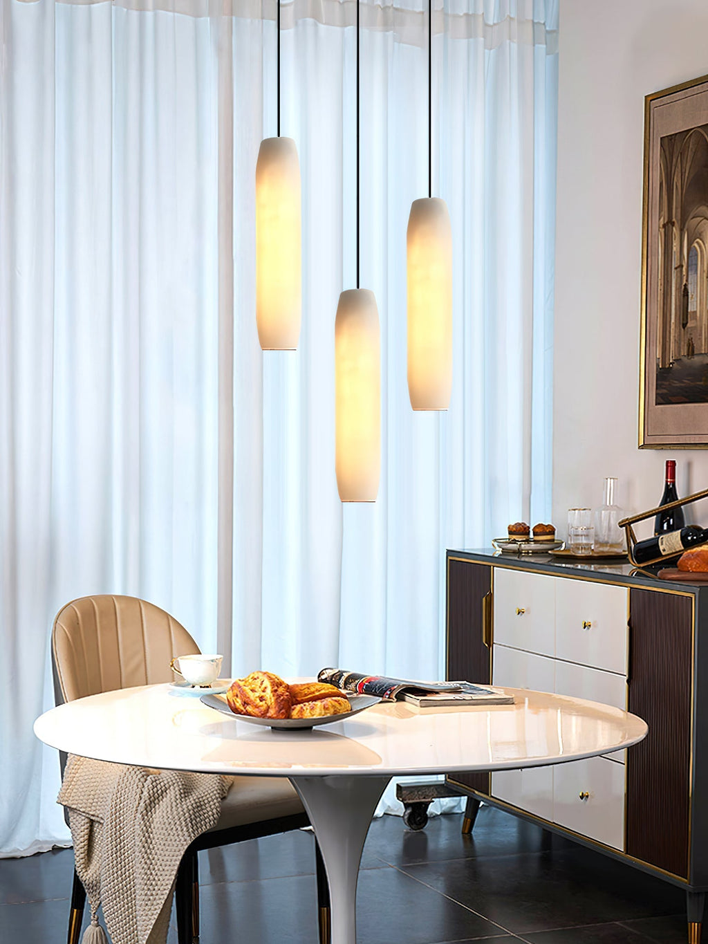 Clérachic stages three Asbury pendants at staggered heights by sheer curtains, above a marble table set for coffee.