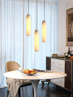 Clérachic stages three Asbury pendants at staggered heights by sheer curtains, above a marble table set for coffee.