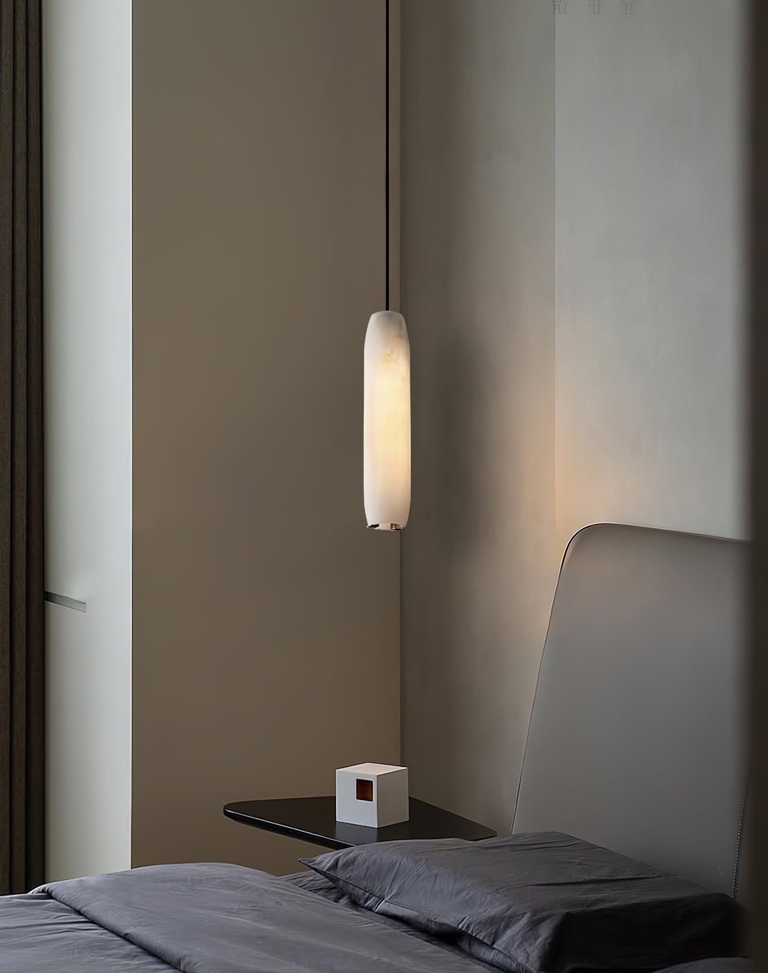 The Clérachic Asbury hangs over a floating nightstand in a bedroom dressed in charcoal linen and warm grey walls.
