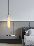 The Clérachic Asbury drops beside a panelled headboard, lighting a slim floating shelf holding two glass tumblers.