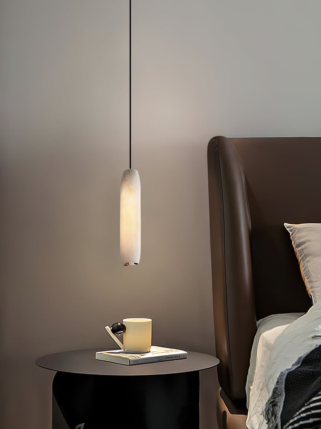 Clérachic hangs the Asbury above a black round side table with a yellow mug, beside a tan leather headboard.