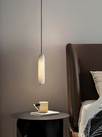 Clérachic hangs the Asbury above a black round side table with a yellow mug, beside a tan leather headboard.