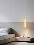 Clérachic drops the Asbury over a built-in bedside ledge, its warm light washing the pale wood headboard behind.