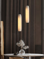 Clérachic hangs two Asbury pendants at different heights against heavy curtains, over a round marble cafe table.