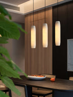 The Clérachic Asbury lines up three shades over a dining table, against slatted oak panelling seen past green leaves.