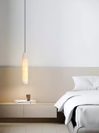 The Clérachic Asbury hangs in a bright minimal bedroom, lighting a low white console beside crisp white bedding.