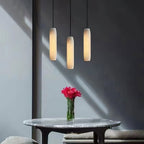 Clérachic groups three Asbury pendants at staggered drops on a sunlit grey wall, over a marble table with carnations.