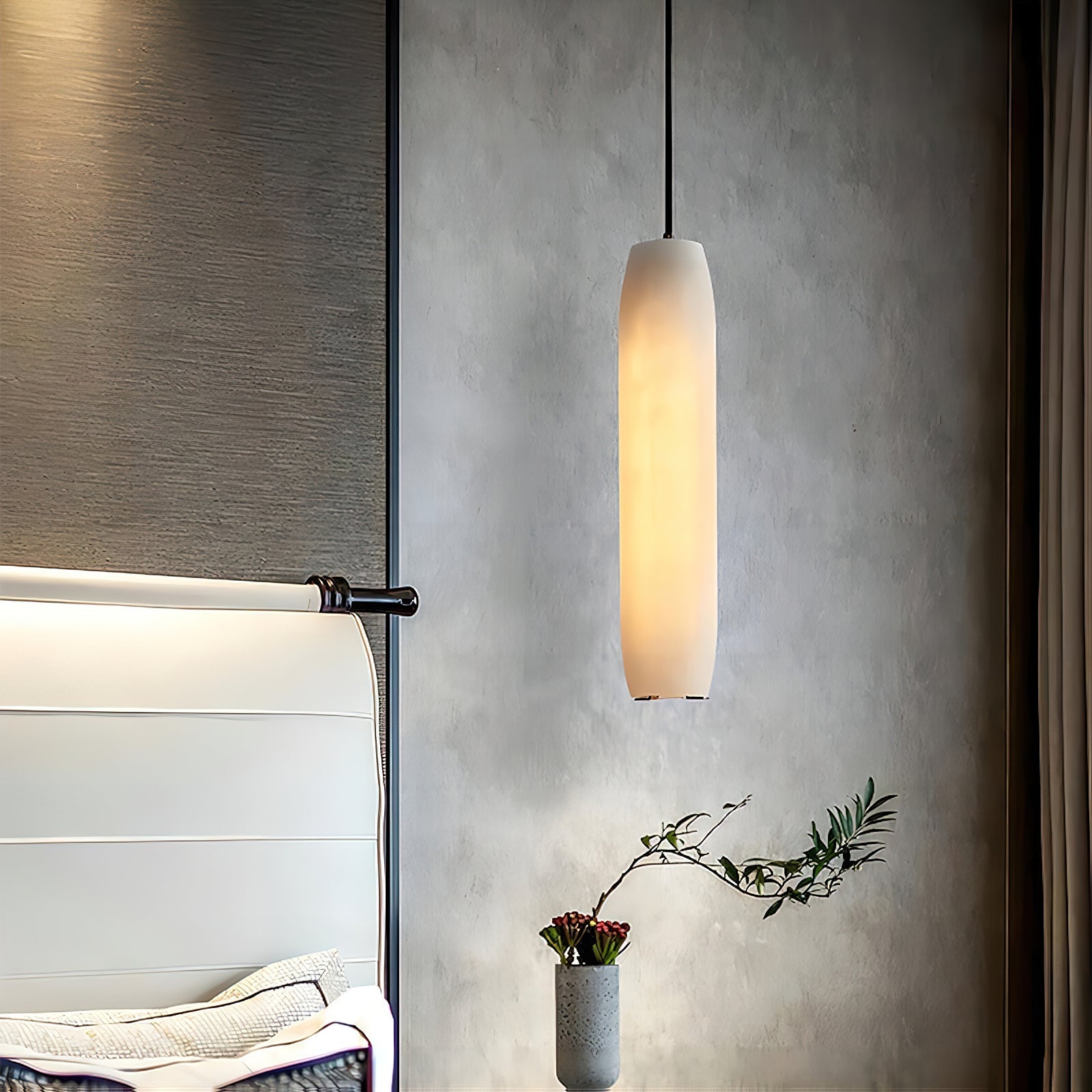 The Clérachic Asbury seen from the foot of the bed, its lit shade set against grey plaster and a black wall bracket.