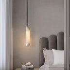 Clérachic hangs the Asbury beside a scalloped grey headboard, lighting a nightstand stacked with books and coral.