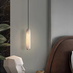 The Clérachic Asbury glows beside a faceted white bust and a brown leather headboard, framed by dark marble.