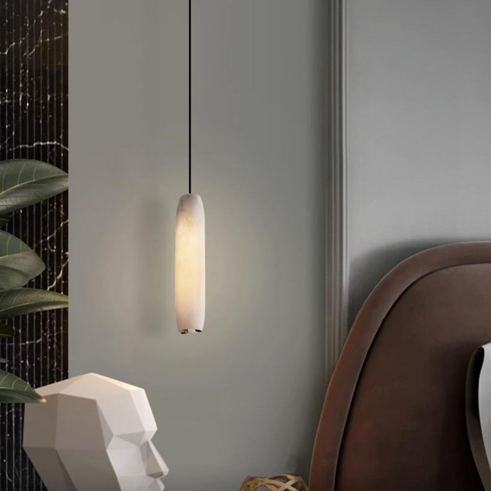 The Clérachic Asbury glows beside a faceted white bust and a brown leather headboard, framed by dark marble.
