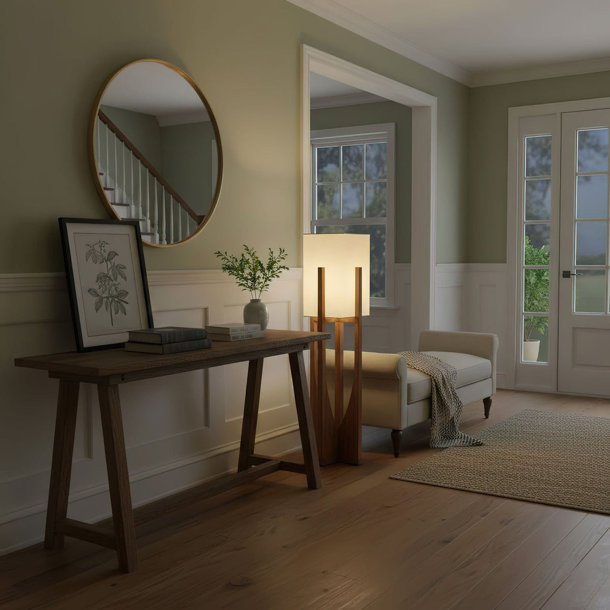 Floor lamp from Clérachic beside a dark console table with a round mirror, a framed print and a small plant above.