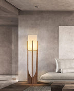 Lit Clérachic floor lamp in a concrete-walled living room, beside a pale sofa and a stone coffee table.