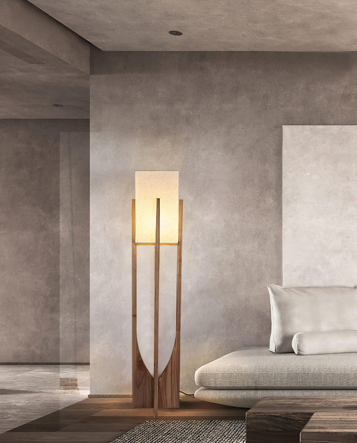 Lit Clérachic floor lamp in a concrete-walled living room, beside a pale sofa and a stone coffee table.