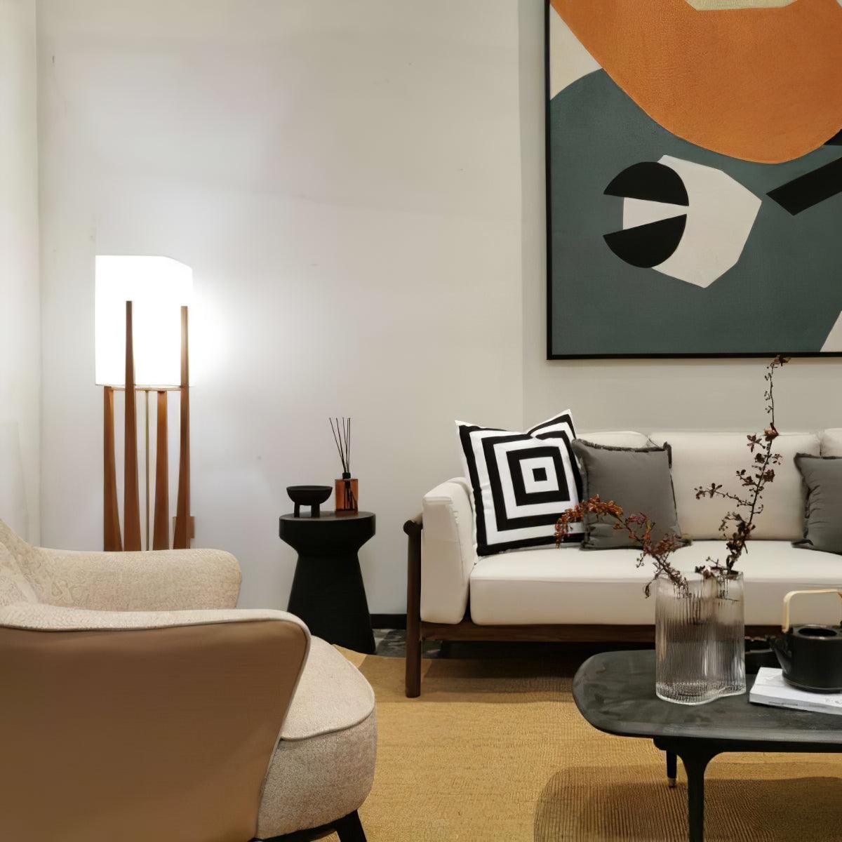 Slim Clérachic floor lamp in the corner of a bright living room, near a cream sofa, a black side table and a bold abstract painting.