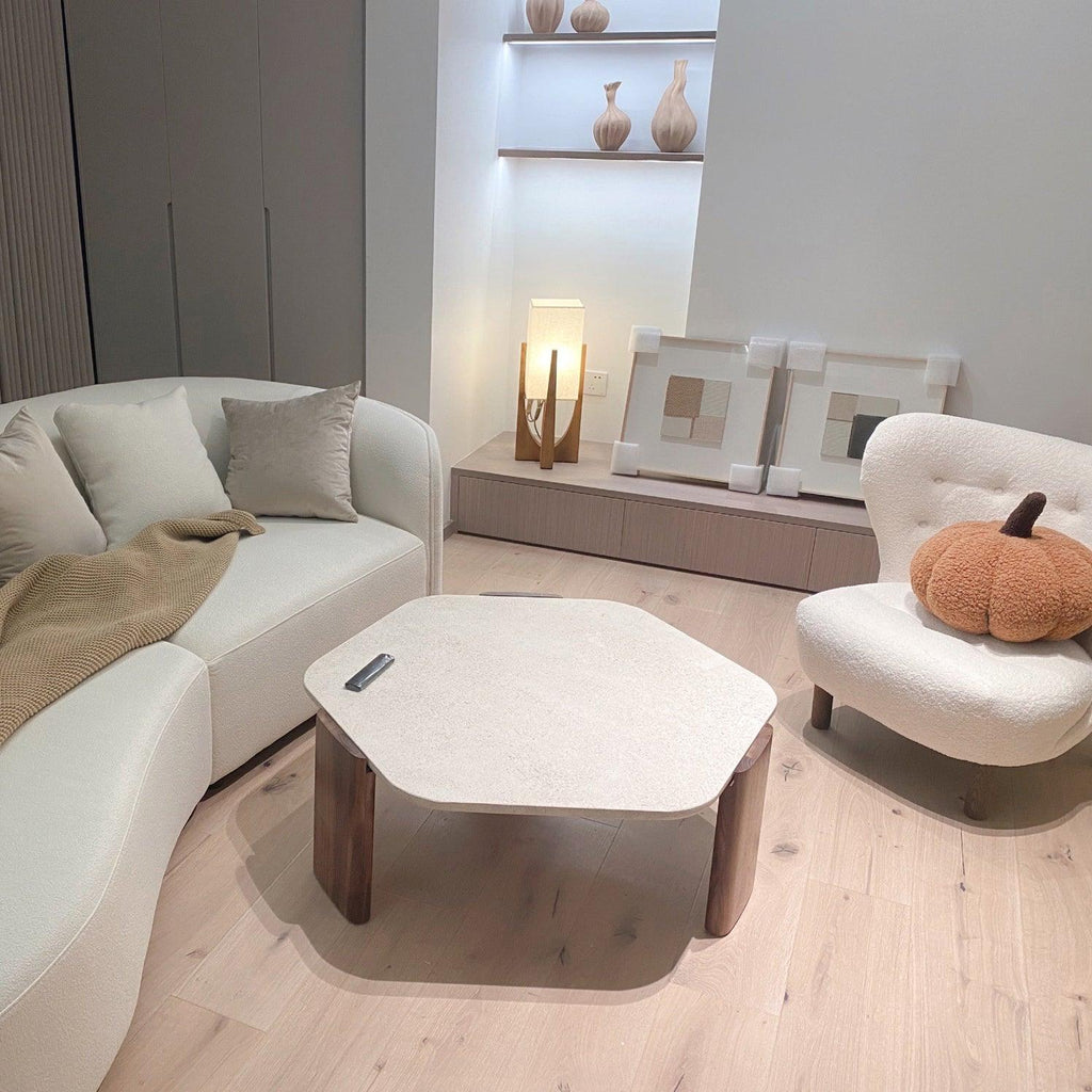 Small Clérachic floor lamp lit in a living room with a cream curved sofa, a hexagonal stone table and a boucle armchair.