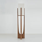 Dark wood floor lamp from Clérachic with an unlit fabric shade, on a pale grey backdrop, with the curved cut-out showing.