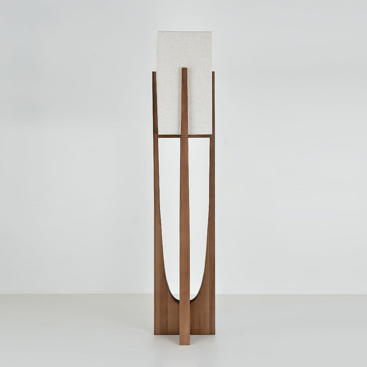 Dark wood floor lamp from Clérachic with an unlit fabric shade, on a pale grey backdrop, with the curved cut-out showing.